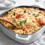 Orzo Tuscan Chicken Bake in a white casserole dish with melted cheese and tomatoes.