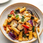 A vibrant bowl of Roasted Vegetable Pasta with charred tomatoes and basil.