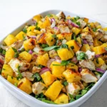 Fresh Mango Chicken Salad with grilled chicken and sliced mango in a wooden bowl.