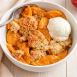 Fresh Apricot Crisp with melting vanilla ice cream in a baking dish.